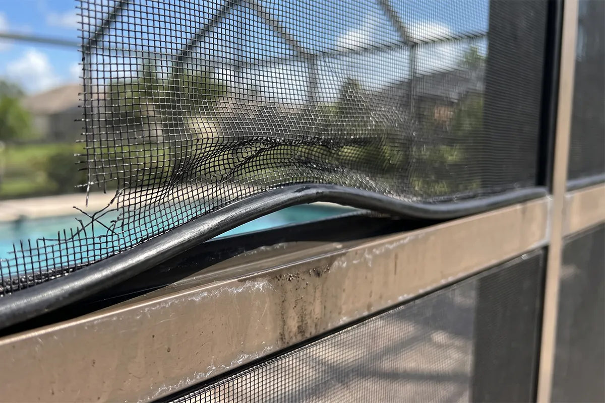 Pool cage screen and frame damage caused by high-pressure washing, stretched mesh and lifted spline