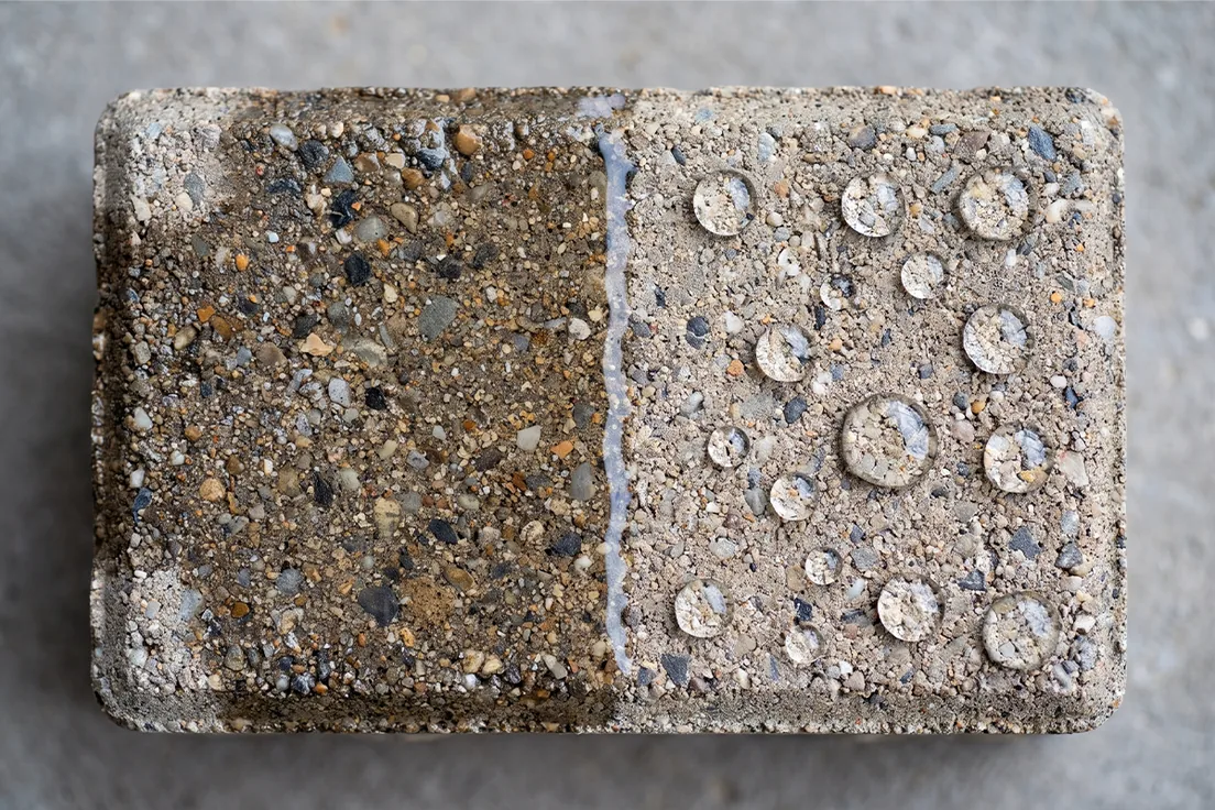 Water beading on a sealed paver next to the same paver unsealed and absorbing water