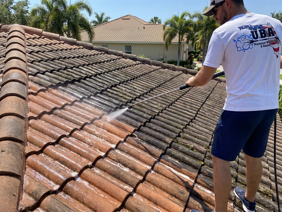 UBA White Team soft washing a Florida tile roof, cleaned and untreated sections visible