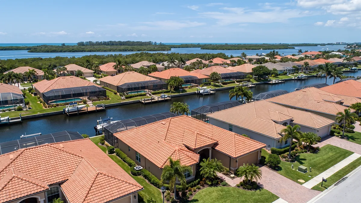 Aerial view of a Venice FL canal neighborhood with cleaned tile roofs and pool cages
