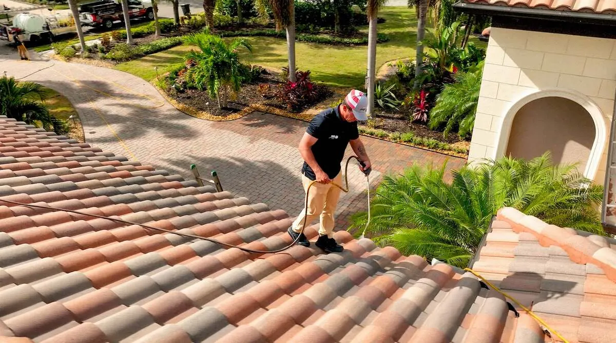 Aerial close-up of UBA technician applying soft wash solution to Florida clay barrel tile roof in a Sarasota neighborhood