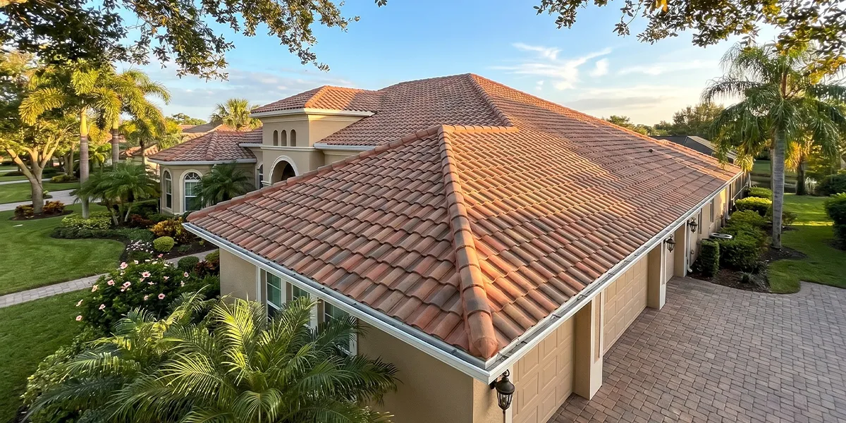 Florida tile roof home in Sarasota with clean gutters, aerial view with tropical landscaping