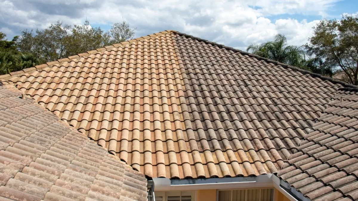 Sarasota tile roof during a UBA soft wash, the left side cleaned back to its original tan color and the right side still darkened with algae and dirt